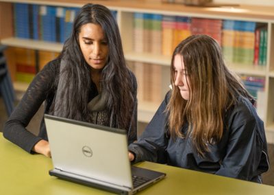 Teacher and student at the library looking at laptop screen