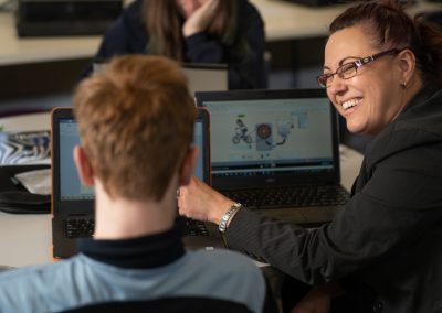 Teacher pointing at computer screen to student
